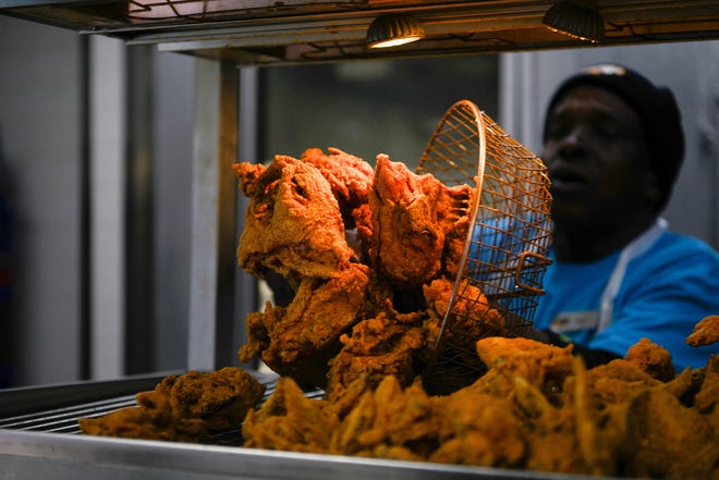 A chef tosses freshly fried chicken on a tray as diners gather at Frenchy's Chicken, a Houston-based restaurant chain that got a nod in the movie